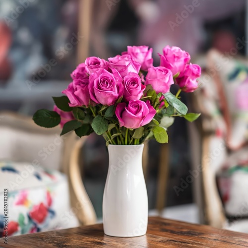 Bright Pink Roses in a White Vase on a Wooden Table in a Living Room Setting