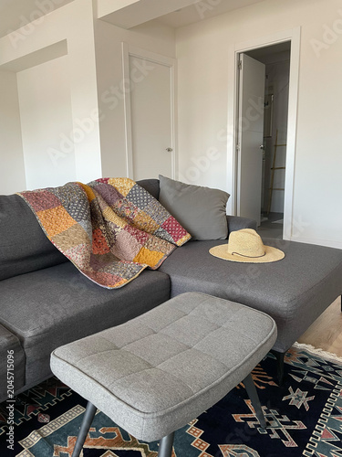 Soft blanket placed on gray couch in modern living room showing a door and a hat located nearby