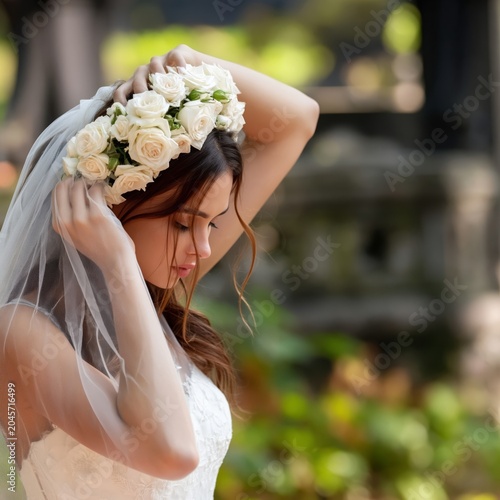 Bride Adjusts Her Flower Crown in a Garden During a Wedding Ceremony