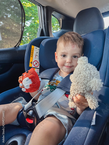 Toddler in rear car seat holding plush toys