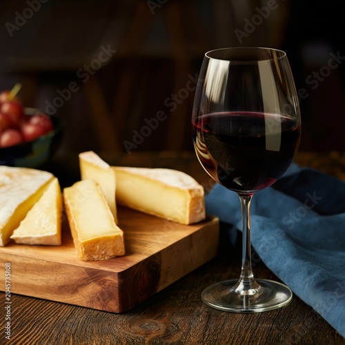 Enjoying Red Wine and Cheese on a Wooden Table in a Cozy Setting During the E...