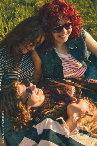 Fotografi Close up of young women resting together on grass with retro effect