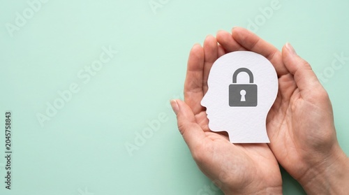 A profile cutout of a human head with a lock symbol on it, held between two cupped hands, signifying mental security or privacy