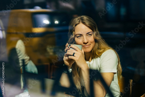 Smiling businesswoman enjoying hot coffee during break from work at office
