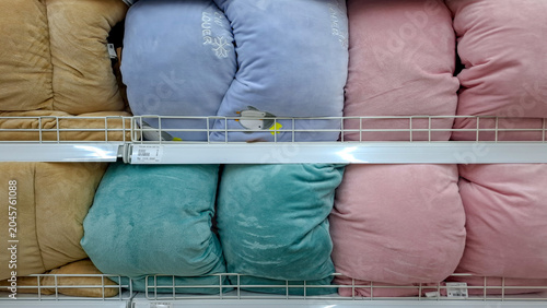 Bild auf Leinwand Row of vibrant soft plush pillows in pink teal blue and beige colors neatly organized on a retail metal shelf