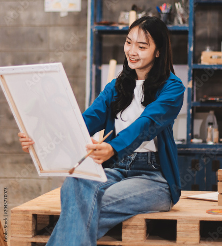 Female artist wears black hat posing near picture indoor the studio