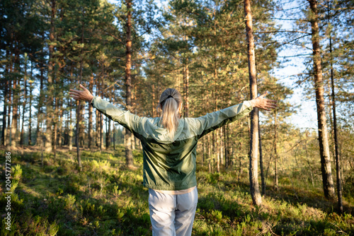 Εκτύπωση καμβά Active woman nature lover walking in woodlands, stands with spread arms in fores