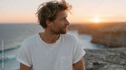 A captivating profile of a man illuminated by the warm glow of a sunset, capturing a moment of serenity and reflection by the ocean waves and scenic cliffs.