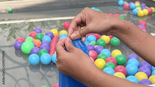 Foto Hands Holding Blue Bag with Colorful Plastic Balls in Children's Play Activity