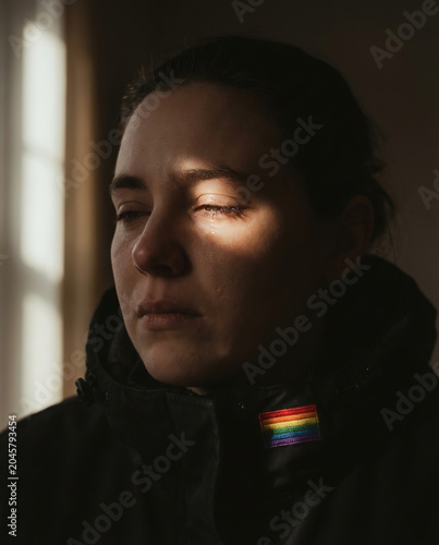 A concerned LGBTQ individual sits in dramatic light, expressing anxiety, emotional struggle, identity challenges, mental health awareness, and resilience.