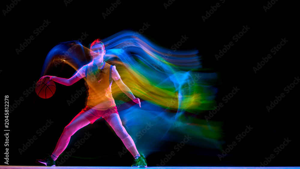 Naklejka premium Focused female basketball player dribbling wide with neon light trail. Concept of basketball advertising, performance branding, agility training promotion, and modern sports posters.