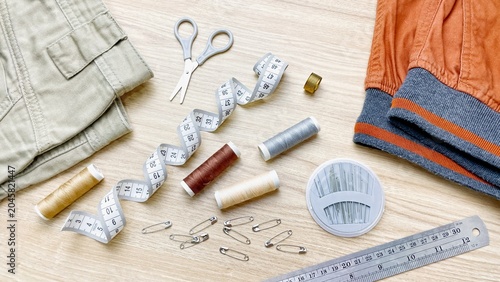 Fotografía An arrangement of sewing supplies and clothing items on a light wooden surface