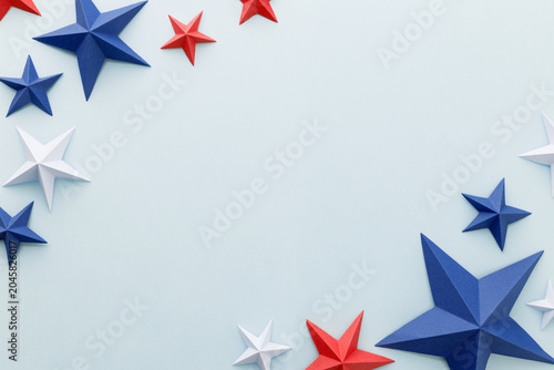 Red, white and blue origami paper stars on a light blue background with large copy space, ideal for patriotic advertising, holiday promotions, greeting cards, invitations, banners posters social media