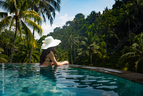 Canvastavla Woman wearing a hat relaxing in an infinity pool with views of lush jungle and rice terraces in Ubud, Bali, Indonesia