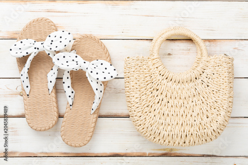 Obraz na płótnie Straw bag with sandals on wooden background, top view