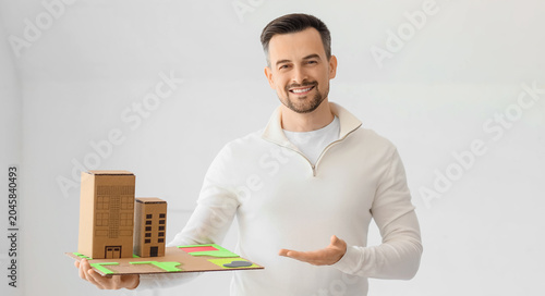 Male architect with 3D house model in office
