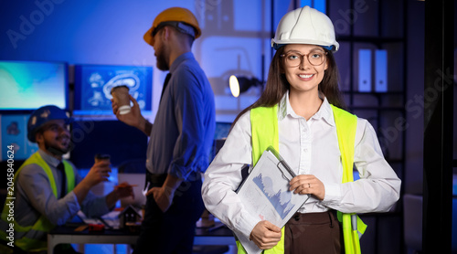 Female engineer with clipboard in office at night
