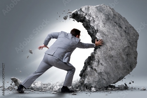 Businessman pushing a giant boulder, symbolizing overcoming obstacles and immense effort in business and life.