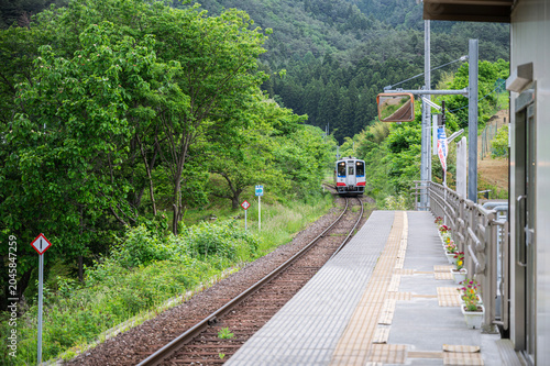 Local train arriving at rural station platform in mountains