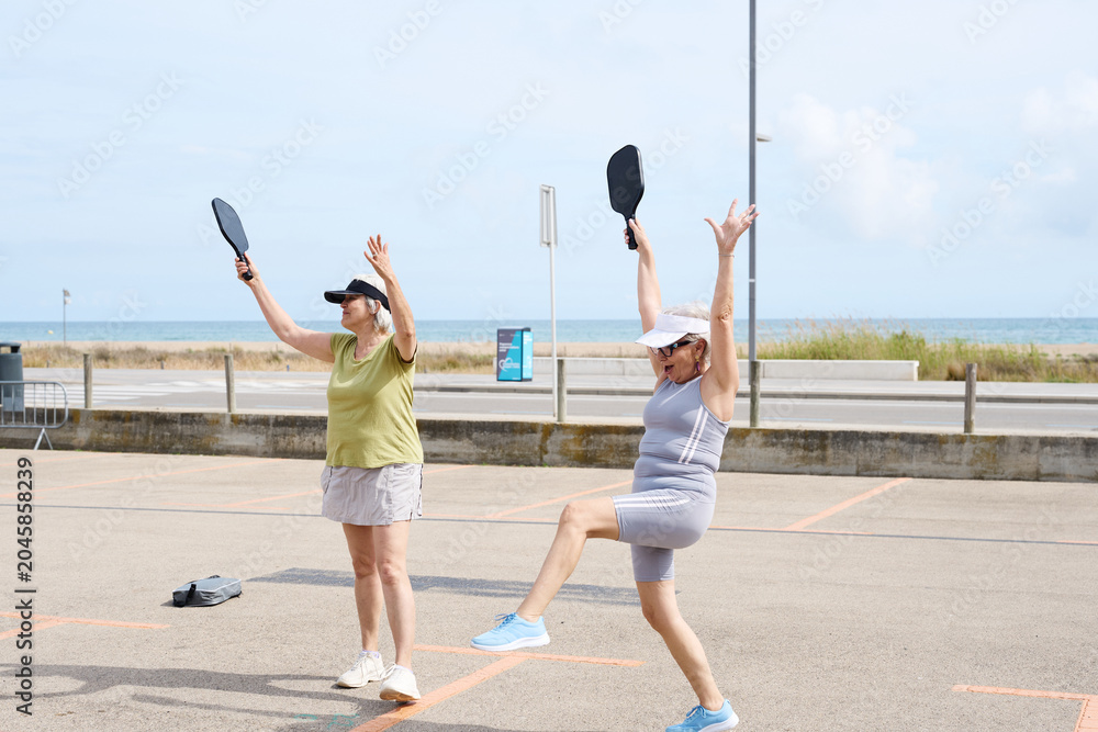 Obraz premium Senior women playing pickleball enjoying active lifestyle