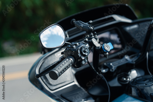 Close up of motorcycle handlebar with focus on control panel and mirror, showcasing intricate details and modern design