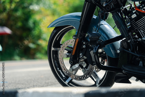 Close up of motorcycle front wheel with shiny disc brake, parked on sunny day
