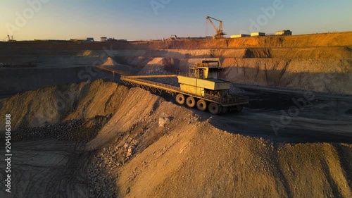Industrial mining machine operating within a vast open pit coal mine during sunset motion video footage