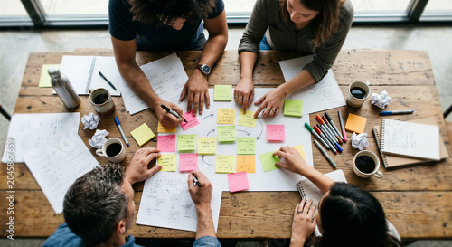 Creative team brainstorming session with sticky notes on wooden table.