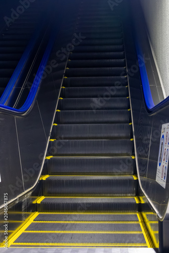 Blue illuminated escalator in modern architectural interior