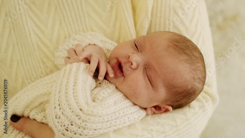 a newborn baby in its mother's arms, the mother soothes the baby before bedtime by rocking it to sleep