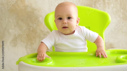 baby in a high chair, small child waiting or asking for food, first solid food, baby food concept