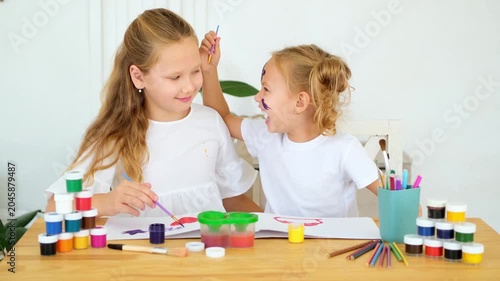 children draw with paints, two girls with painted multicolored hands laugh and indulge on a white isolated background, a place and space for text, small artists and children's creativity