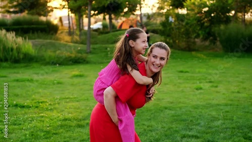 a mother and her child are walking and having fun in the park in the summer, a mother and a small child on a green lawn