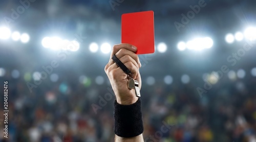 Soccer referee hand holding red card up, football official showing penalty card in stadium, sports discipline and foul concept