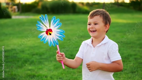 a little boy plays on a green lawn with a spinning top in the summer, having fun, a child walks in the summer evening laughing and smiling, summer holidays