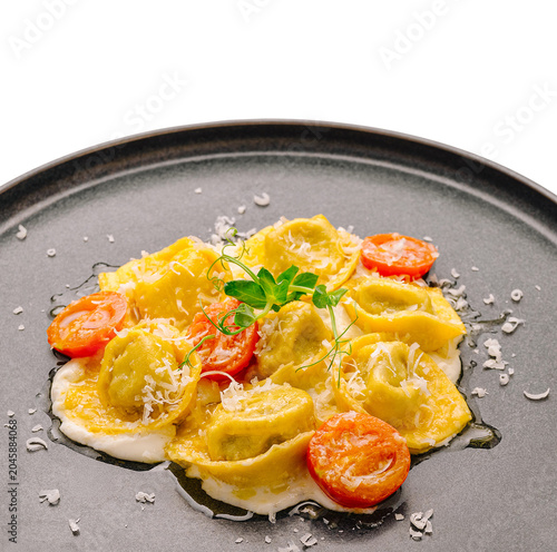 Delicious ravioli dish with tomatoes and cheese served on a black plate