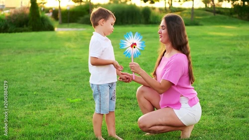 a mother and her child playing on a green lawn in the summer, having fun together, a mother and son walking together on a summer evening, playing a game, laughing and smiling