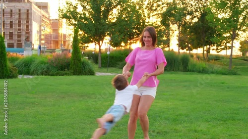 mom and child playing on a green lawn in the summer, having fun together, mother and son walking together on a summer evening
