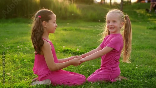children in the park in summer, little girls walking and having fun on a green lawn, playing, summer holidays
