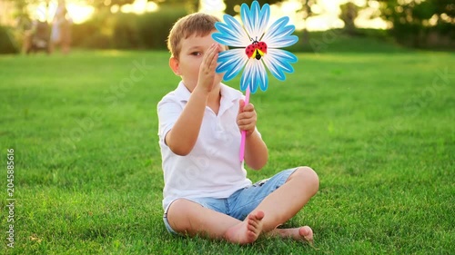 a little boy plays on a green lawn with a spinning top in the summer, having fun, a child walks in the summer evening laughing and smiling, summer holidays