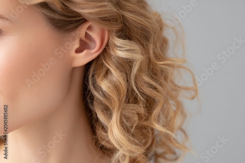 closeup of an ear with blonde, curly hair.