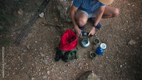 Hiker preparing coffee at campsite with backpack, kettle and portable stove