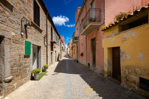 Fotografie Narrow cobblestone street with colorful buildings in Olbia, Sardinia, Italy - ba