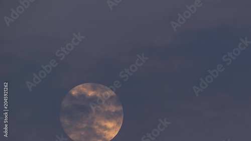 A stunning view of a bright full moon rising in the night sky over Shimen, New Taipei City, Taiwan, with soft clouds partially obscuring the lunar surface.