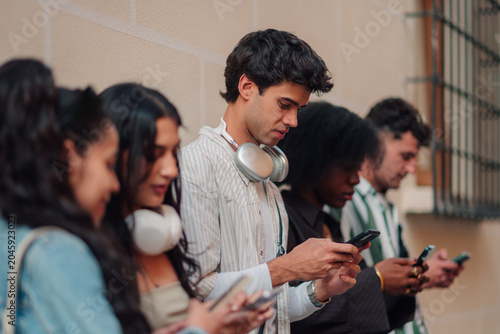 Foto Young people standing in a row, individually engrossed in smartphones, highlight
