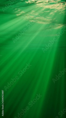 Cinematic underwater sun rays streaming through green ocean surface, illuminating deep water abyss, a mesmerizing natural phenomenon symbolizing tranquility, mystery