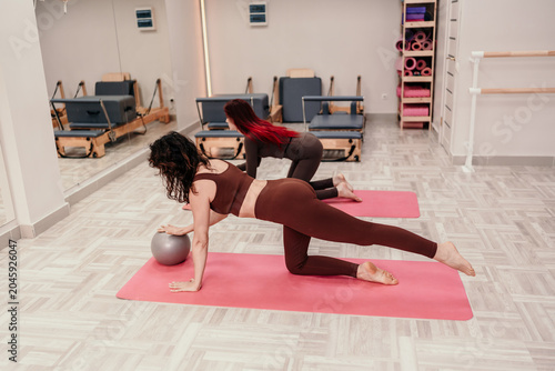 Canvas-taulu Pilates exercise fitness two women perform core strengthening on pink mats in mo