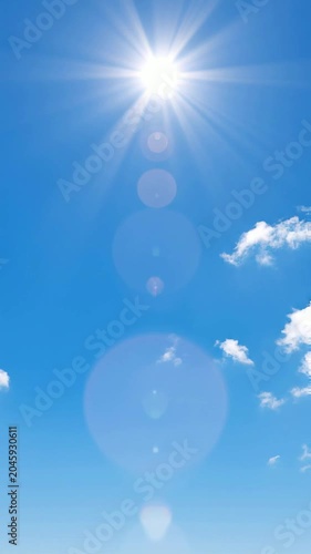 Bright sun shining in clear blue sky with soft clouds