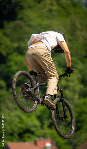 Young cyclist flying through the air on mountain bike during freestyle jump, showcasing athletic skill, adventure lifestyle and extreme outdoor sports