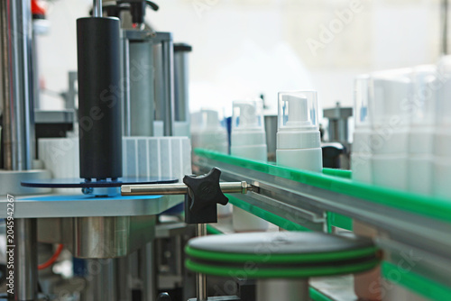 White plastic bottles without labels on conveyor belt. Conveyor belt for cosmetics production. Labeling machine. Cosmetics production